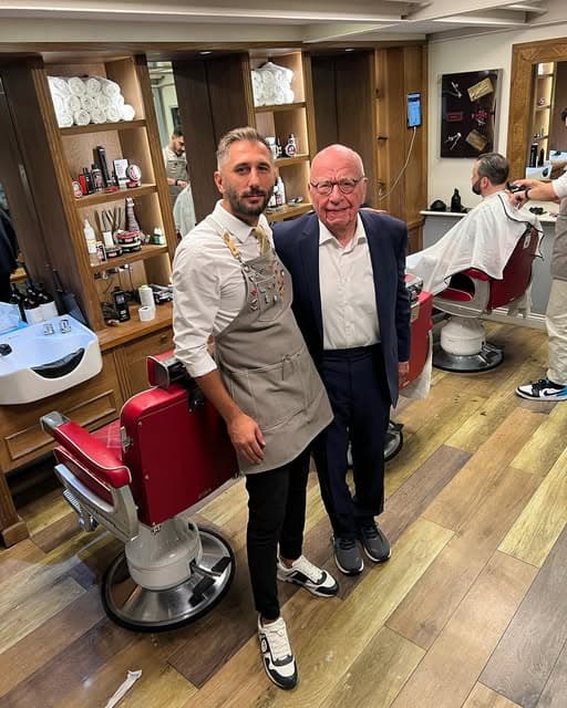 Rupert Murdoch with a Groomsmith barber beside the red chairs