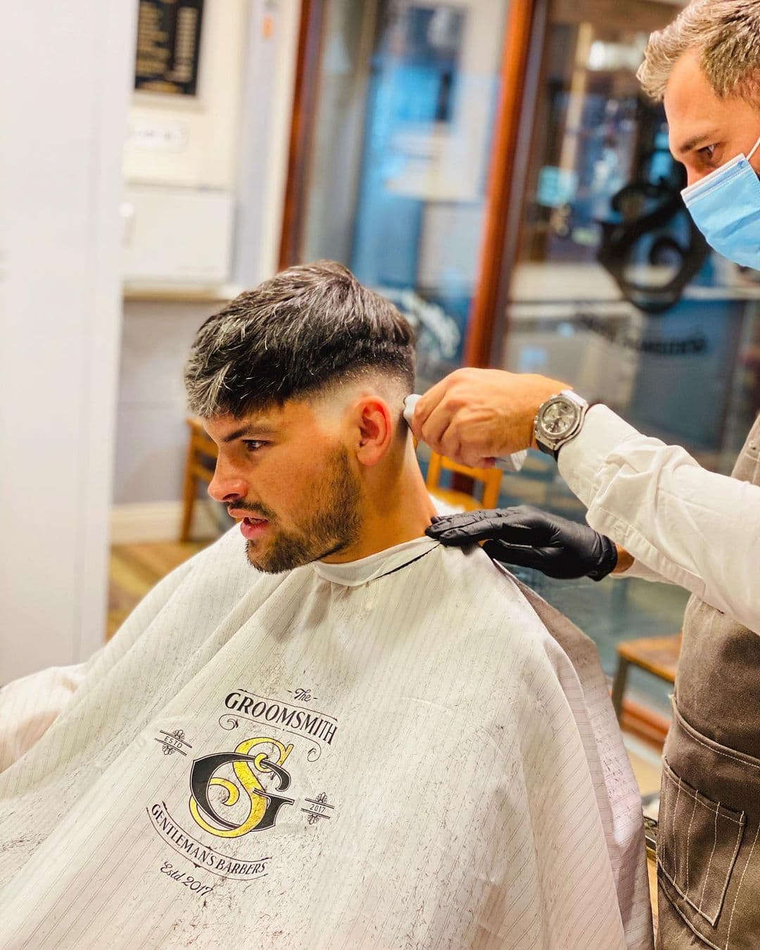 A barber trimming a client at the mirror