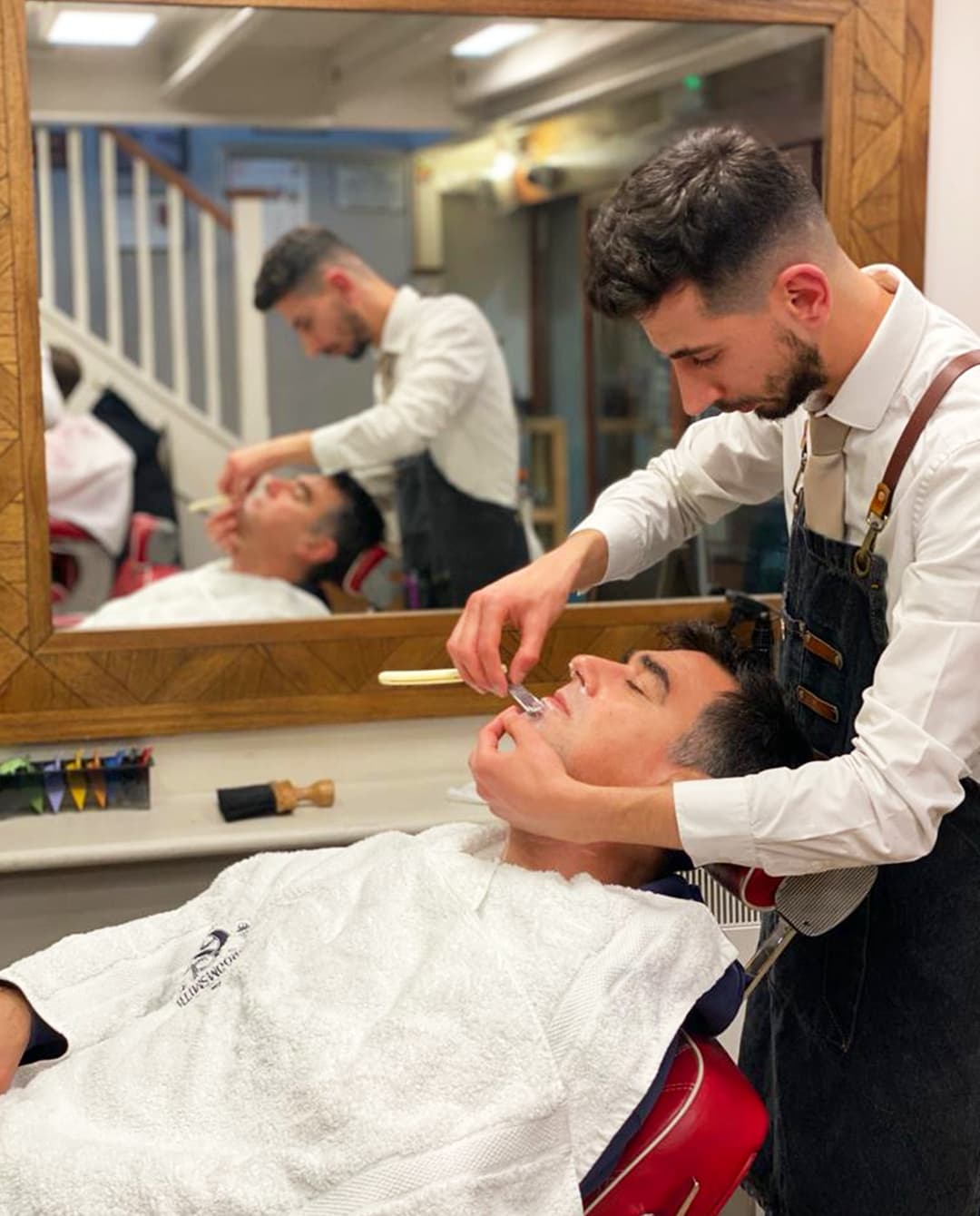 A barber shaping a beard with a straight razor
